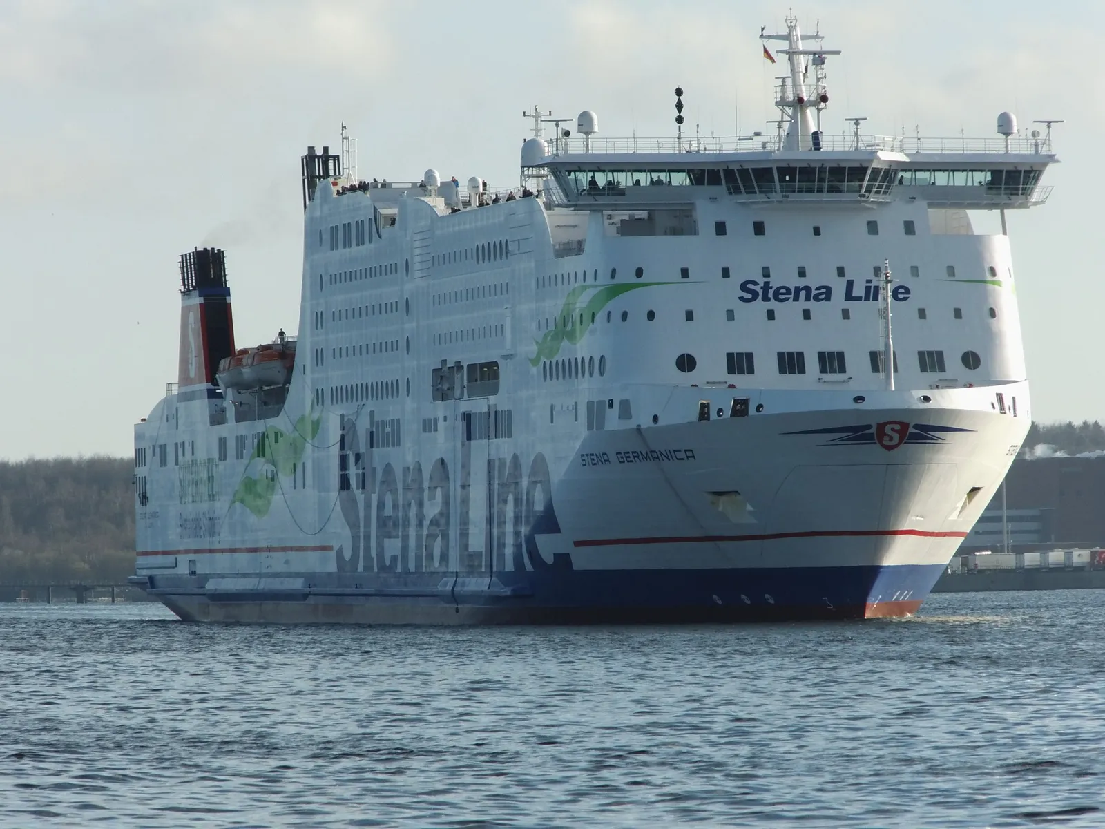 A large white Stena Line ferry with a blue hull sailing in calm water near a harbour.