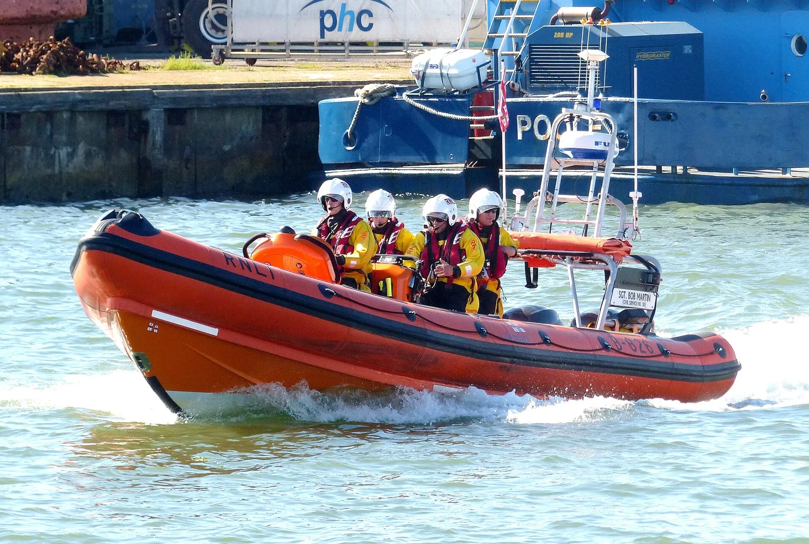 Orange RNLI rigid inflatable lifeboat with four crew at speed