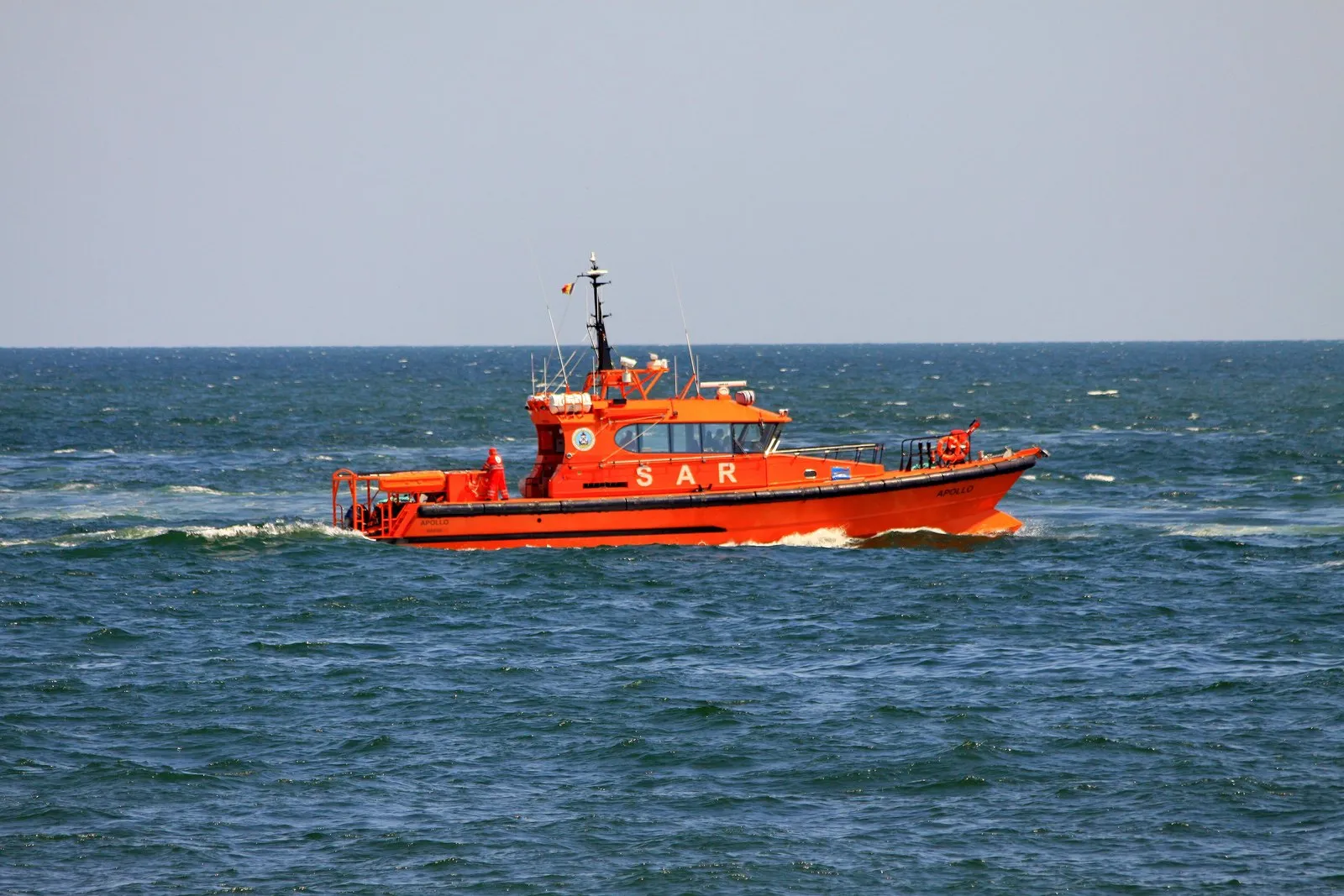 An orange search and rescue boat marked SAR moving at speed on the open sea.