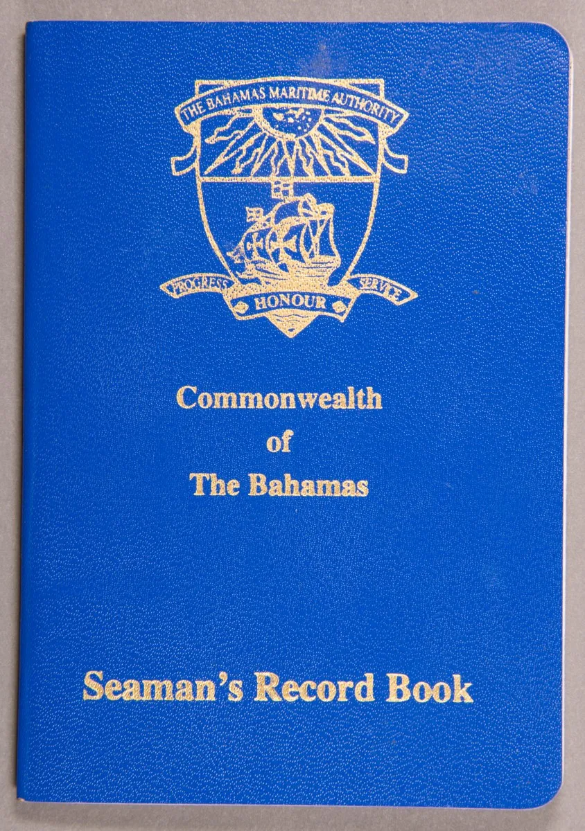 The blue cover of a Bahamas seaman's record book with a gold coat of arms and gold letters.