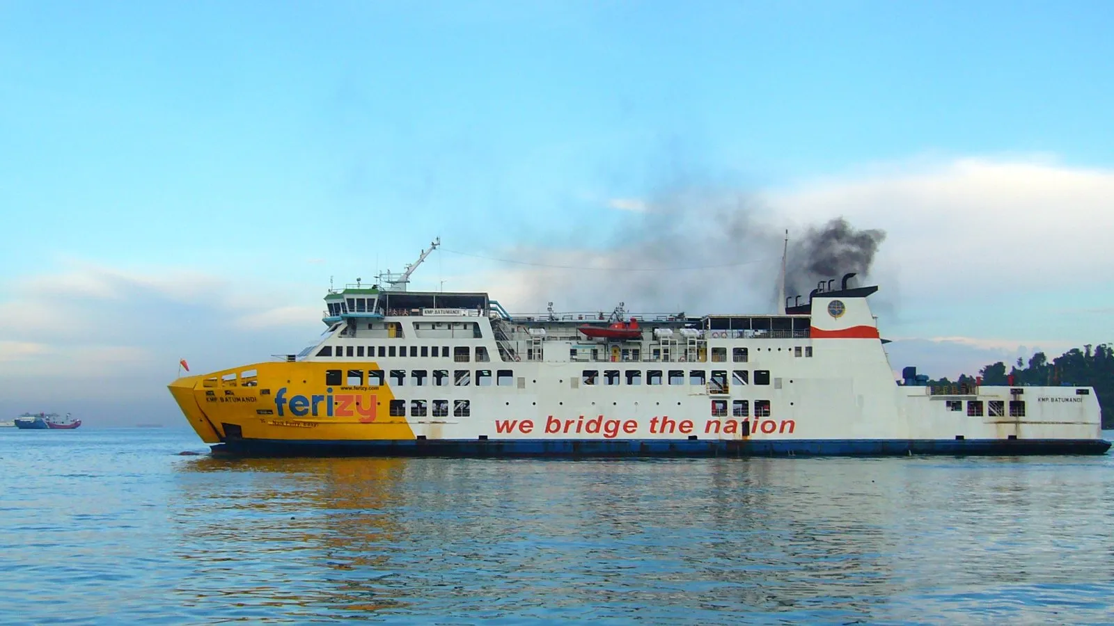 A white ro-ro ferry with a yellow bow and the words we bridge the nation on its side, sailing in calm water.