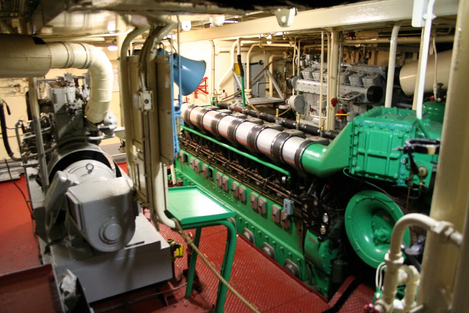 A trawler engine room with a green diesel engine and pipes